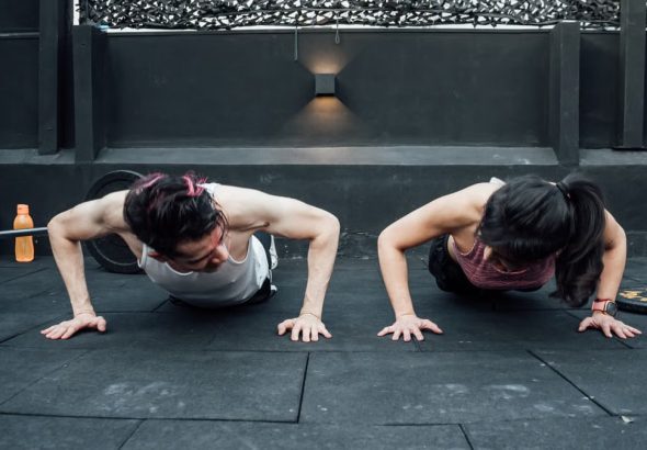 Two adults doing push-ups in an indoor gym setting in Mexico City, promoting a fit and healthy lifestyle.
